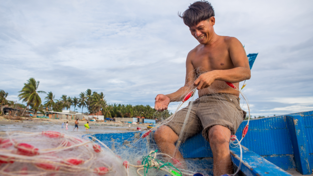man checking a net in a boat