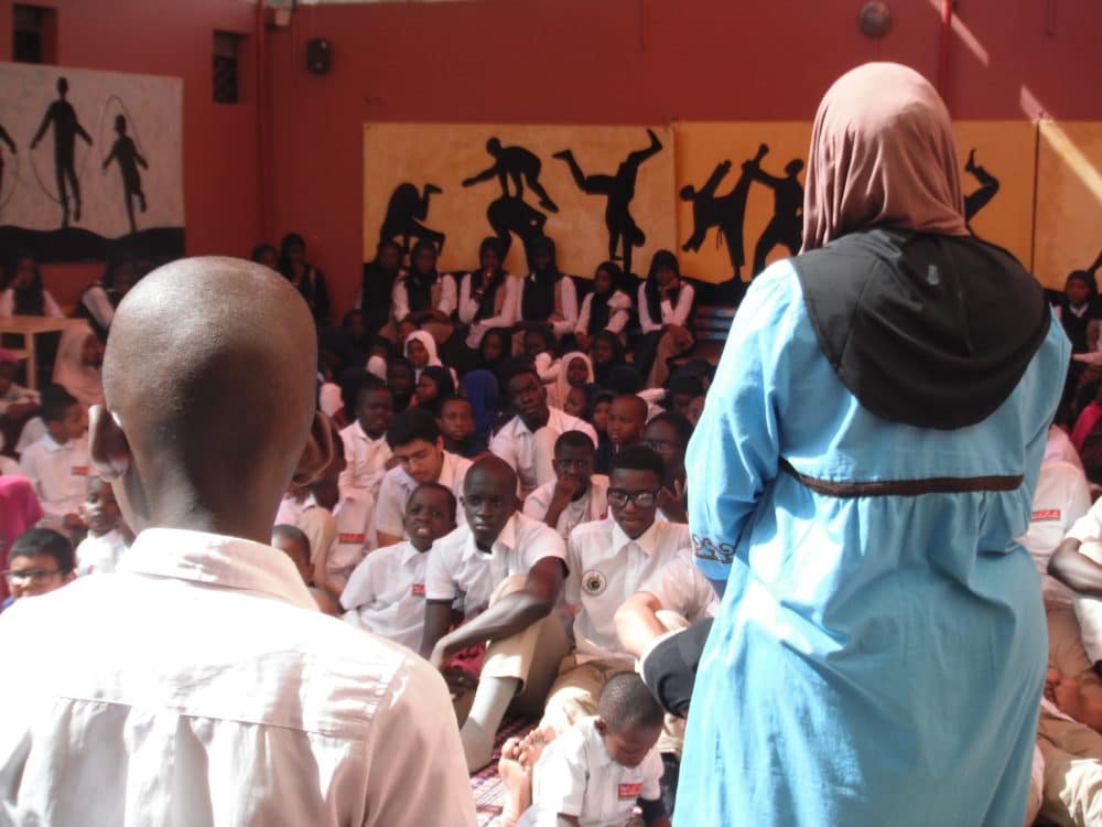 person with back to camera, talking to a group of young men