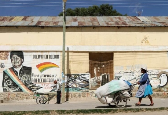 women pushing a trolley against a background of a graffiti wall
